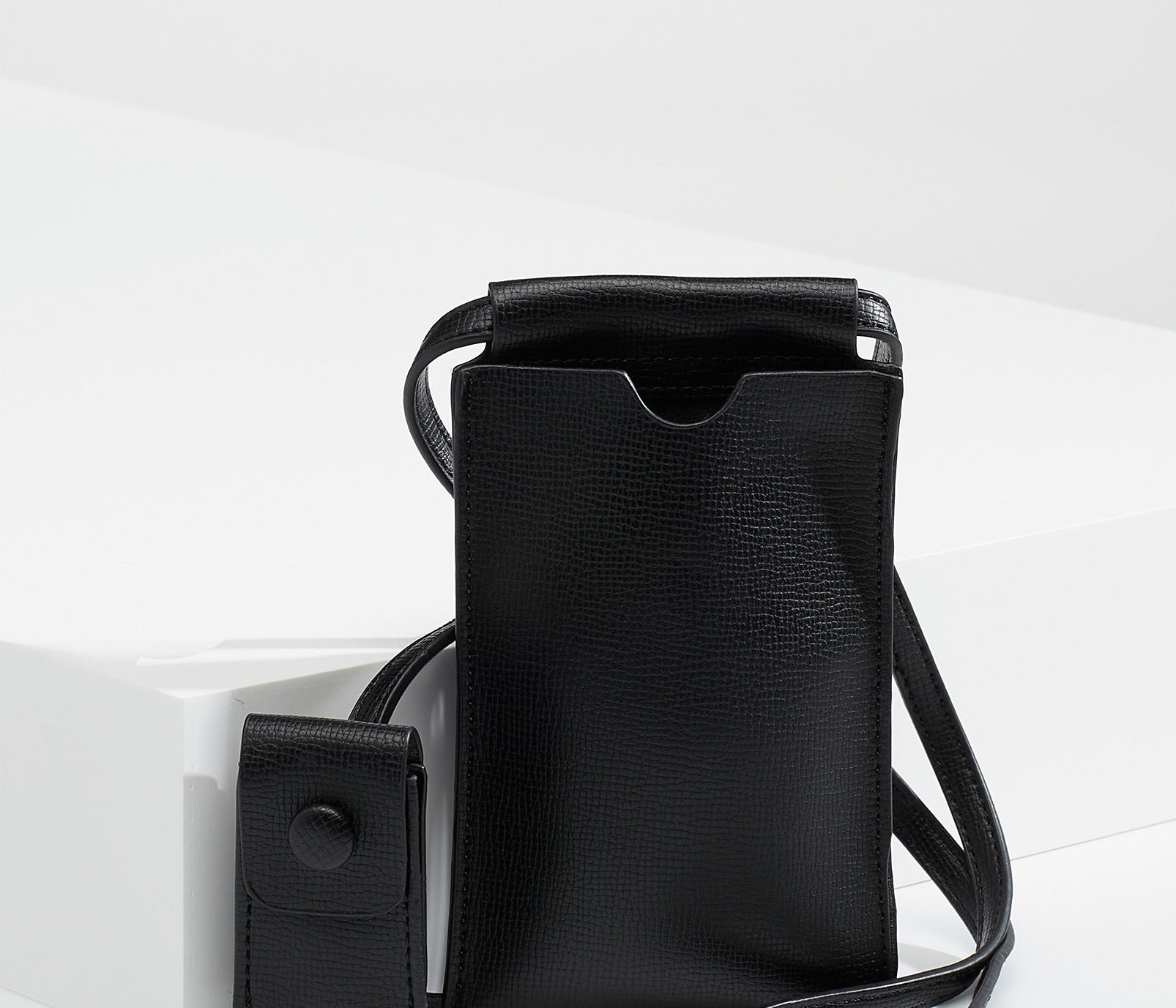A small faux leather bag with a tiny sleeve on the strap for lip balm