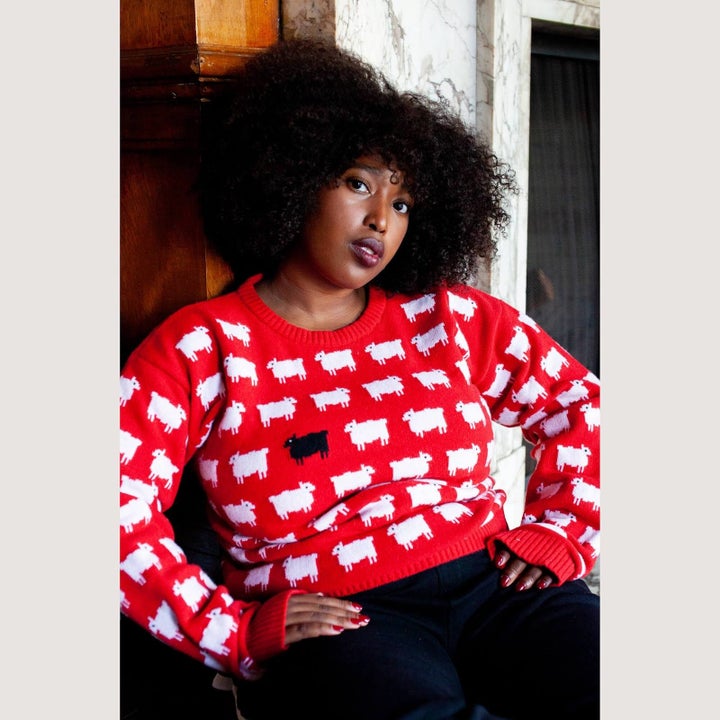 a model wearing the red sweater with sheep on it and one black one