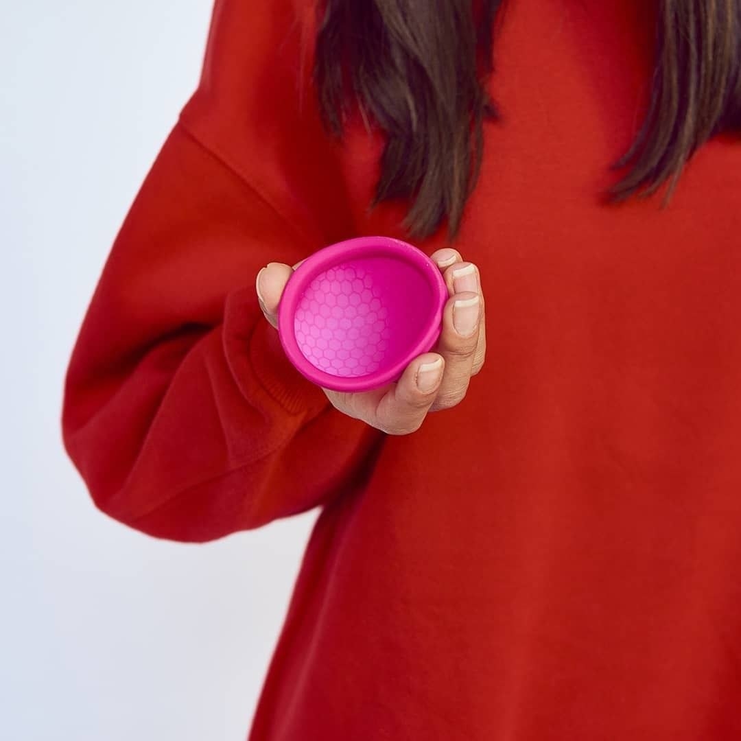 Model holds pink circular Ziggy Cup in hand 