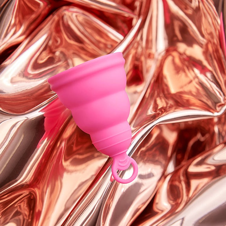 Pink Lily Cup One menstrual cup against a shiny rose gold background