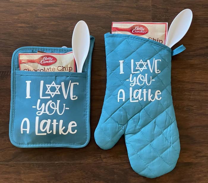 The blue oven mit and pot holder that read &quot;I love you a latke&quot; and have a white spoon in each with a bag of chocolate chip cookie mix