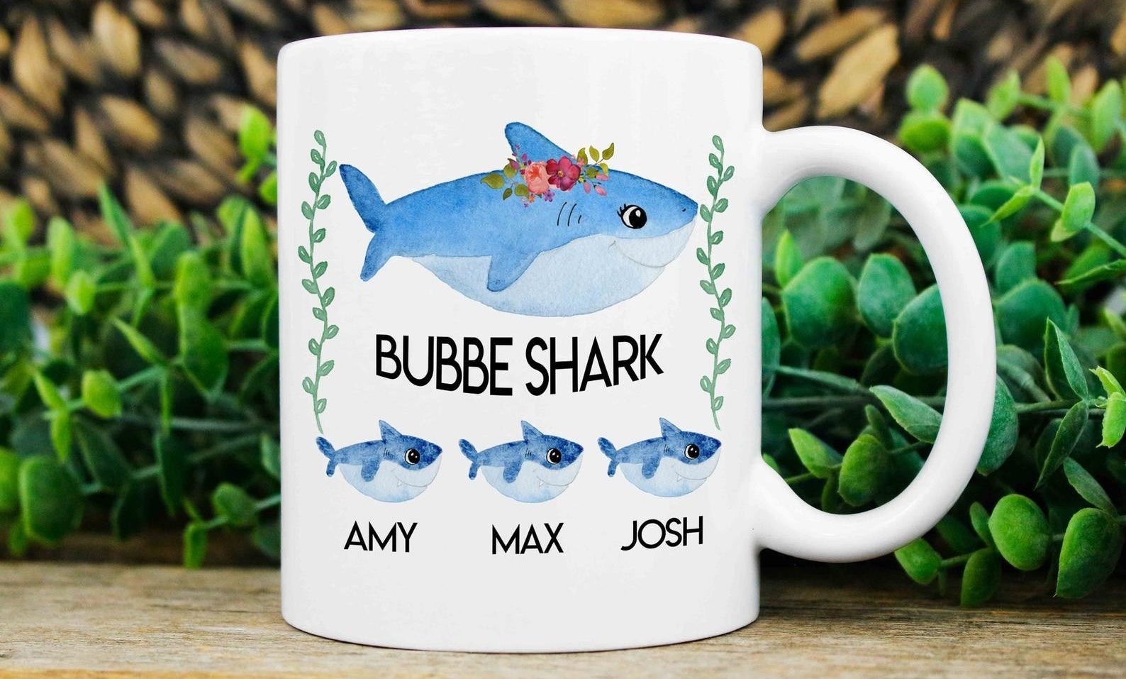the white mug with a big shark that reads bubbe shark underneath with three smaller sharks underneath with grandchildren names under each