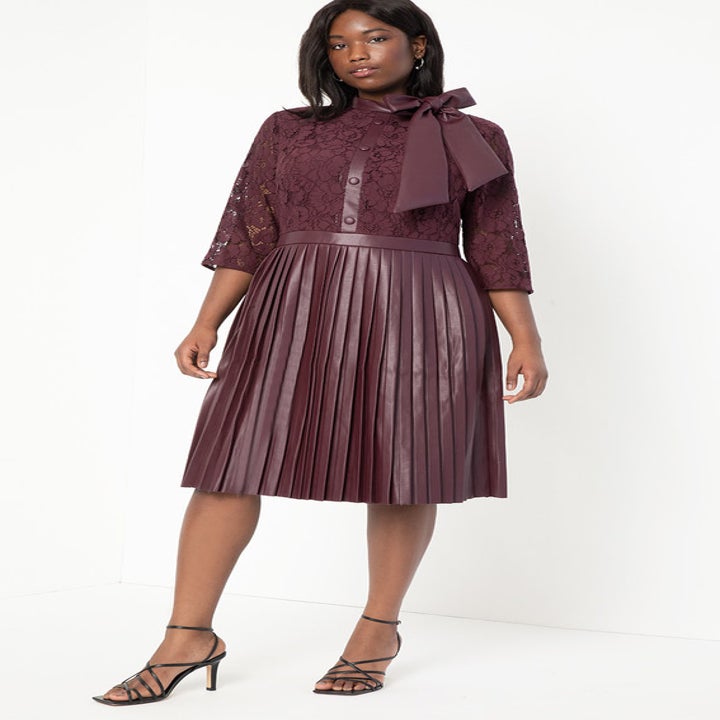A model wearing the dress, which also has a faux leather button detail up the bodice, in burgundy