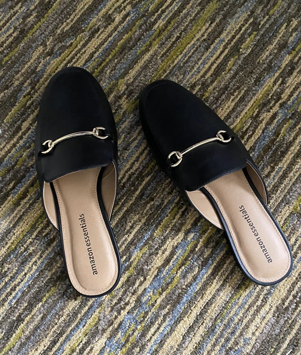 Reviewer image of black mule shoes with a decorative metal buckle on the top of the foot 