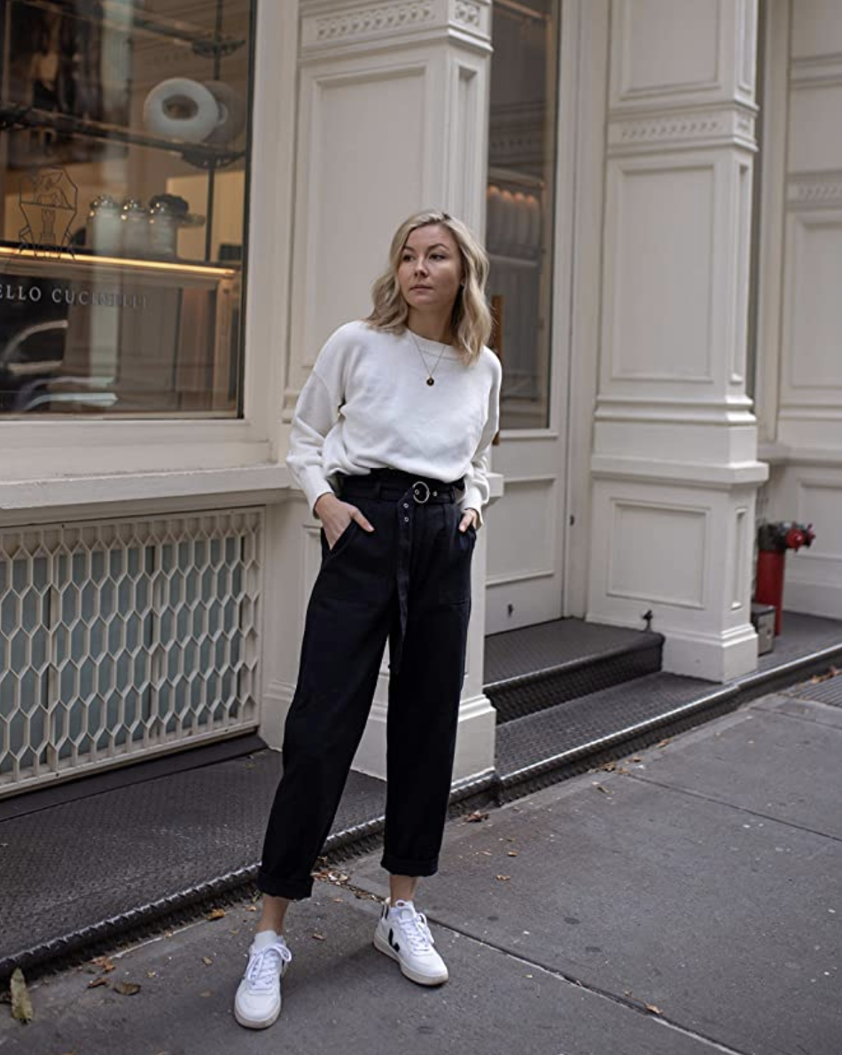 A model in a white sweater with slight balloon sleeves and a crewneck tucked into pants 