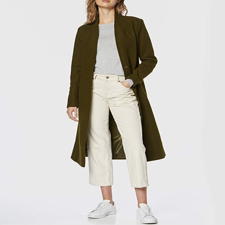Model in olive green mid-calf length coat open to show outfit 