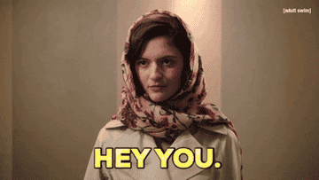 Woman with scarf around head saying &quot;Hey You&quot; to someone