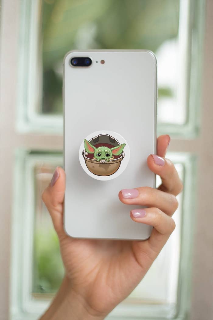 a pop socket with baby Yoda's face on a phone