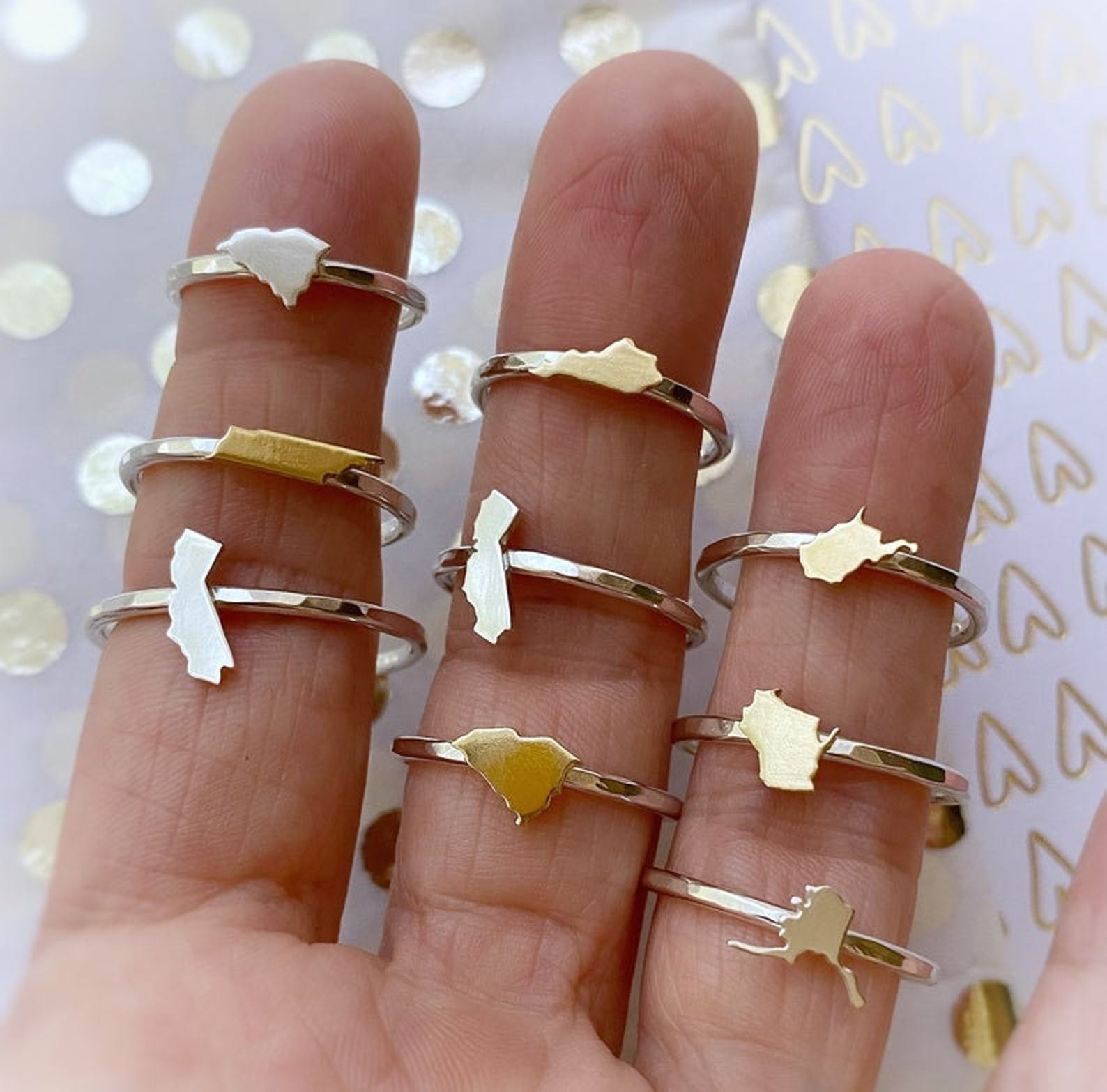 Several dainty rings outlined in various states and modeled around three fingers