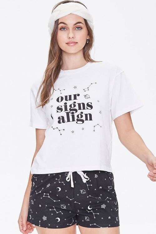 Model wearing black and white PJ set with the graphic &quot;Our signs align&quot; on the T-shirt