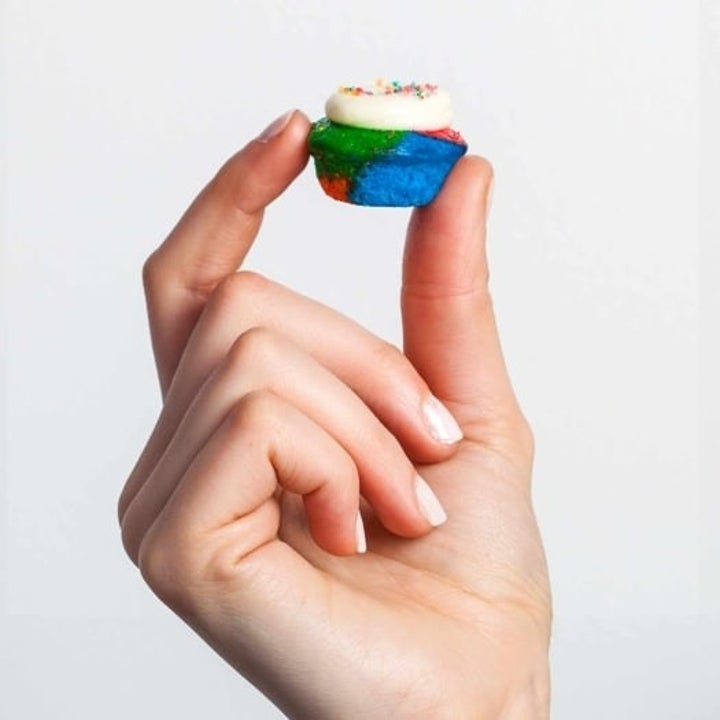 hand holding a tie dye cupcake 