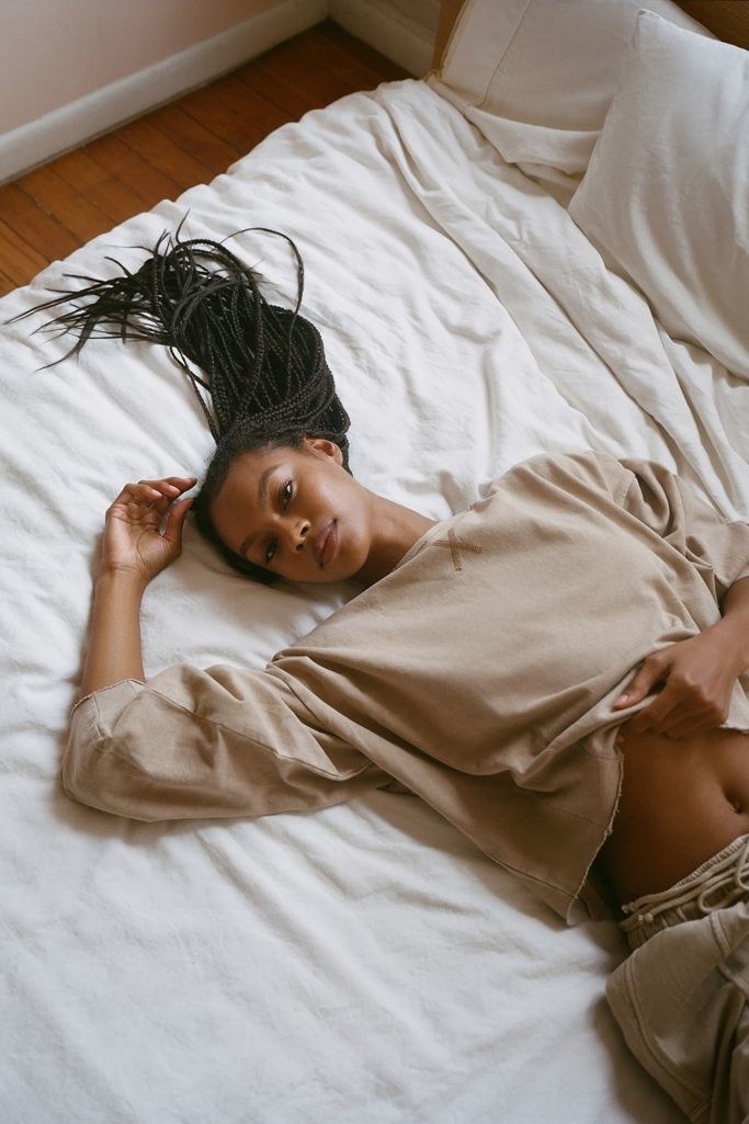 model laying on bed wearing a sweatshirt