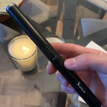 A reviewer holding the lighter with the lit candle in the background