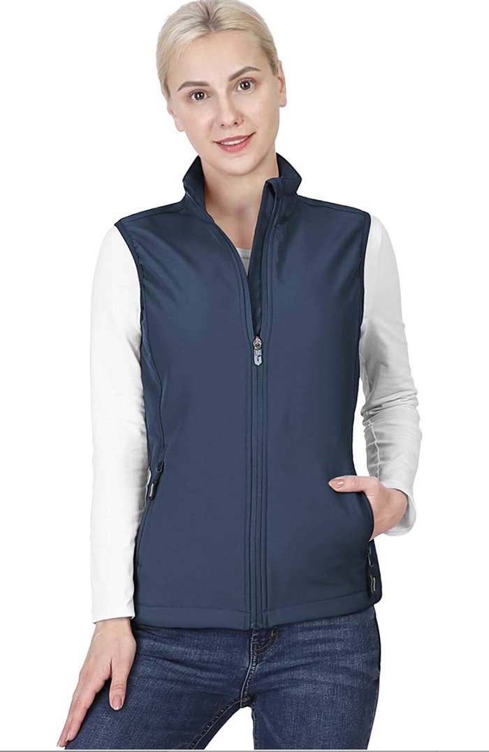 Model in a blue zip up vest with pockets and a high collar 