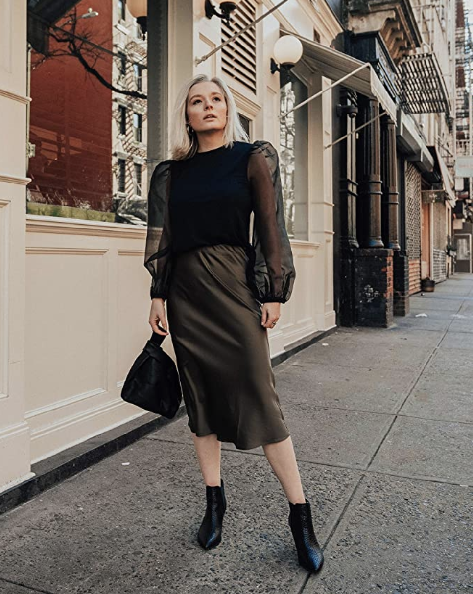 a model in a black silky mid-length skirt 