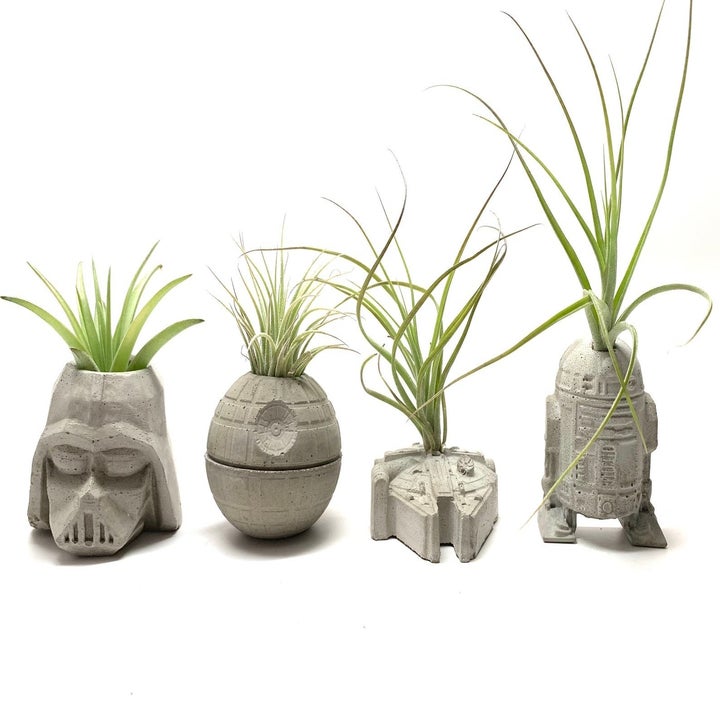 four concrete planters shaped like Darth Vadar, the Death Star, the Millennium Falcon, and R2D2