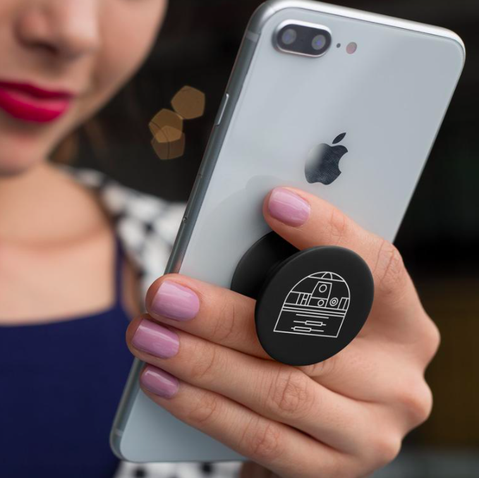 A person using their phone with a Darth Vader pop socket on the back