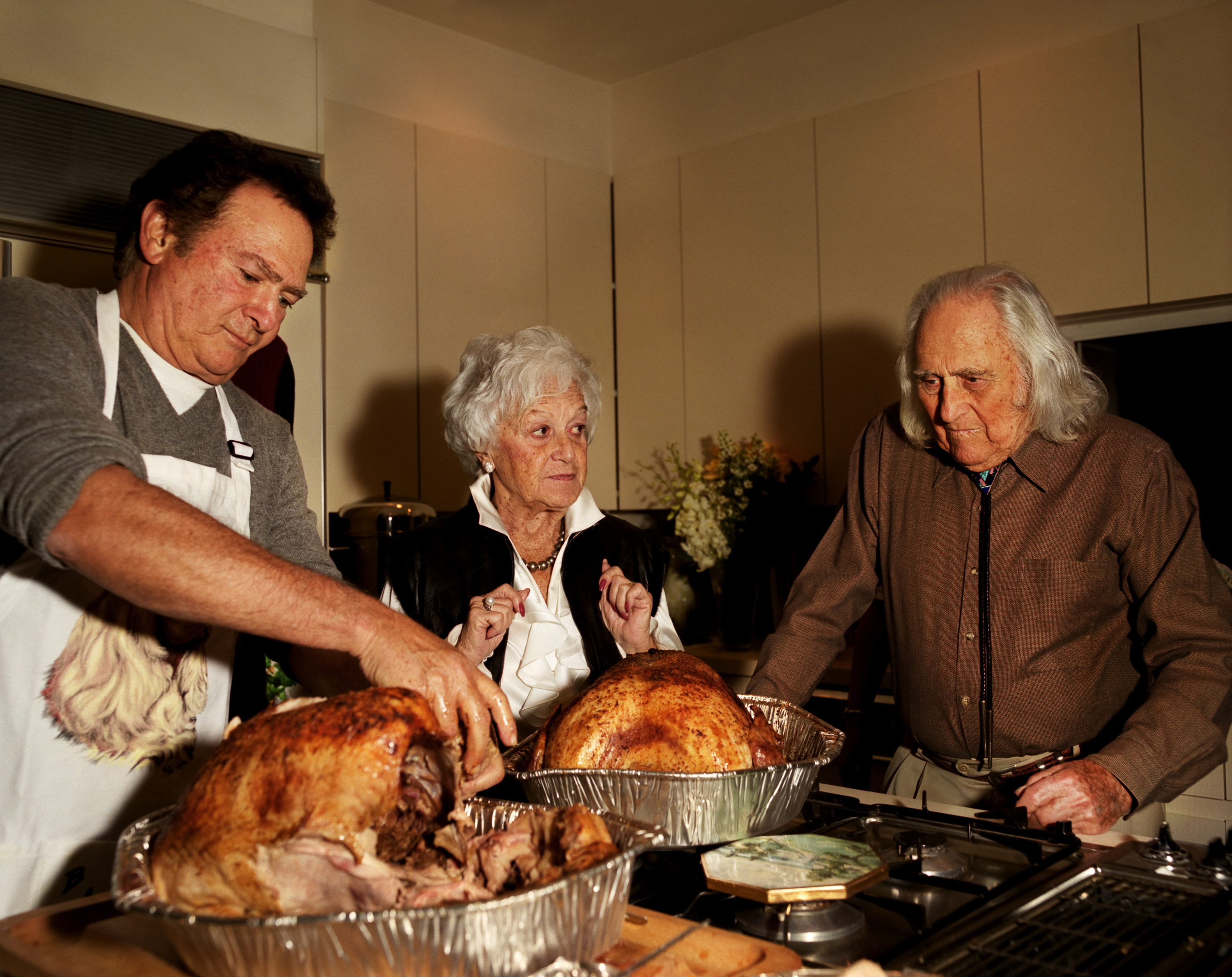 A man, an older woman, and an older man with two turkeys in front of them