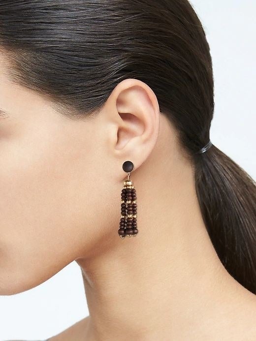 person wearing a brown bead drop earring