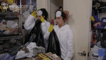GIF of two women in full-body protective suits and face masks preparing to clean a room