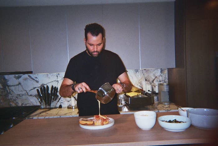 Jeremy pours a sauce on top of a meal in his kitchen