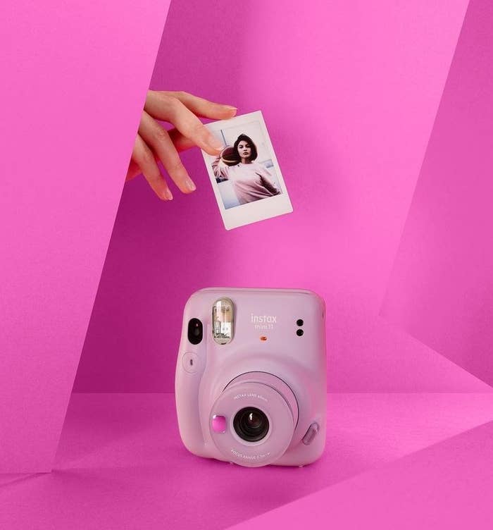 A person lifting a freshly-printed photo from the Fujifilm instax camera