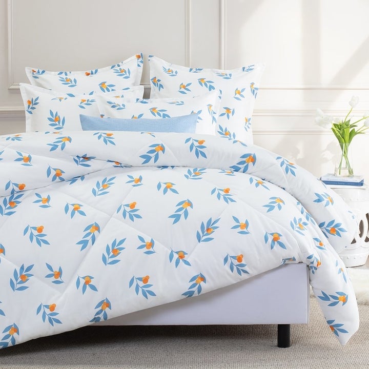 a white comforter with blue leaves and tiny orange flowers on it