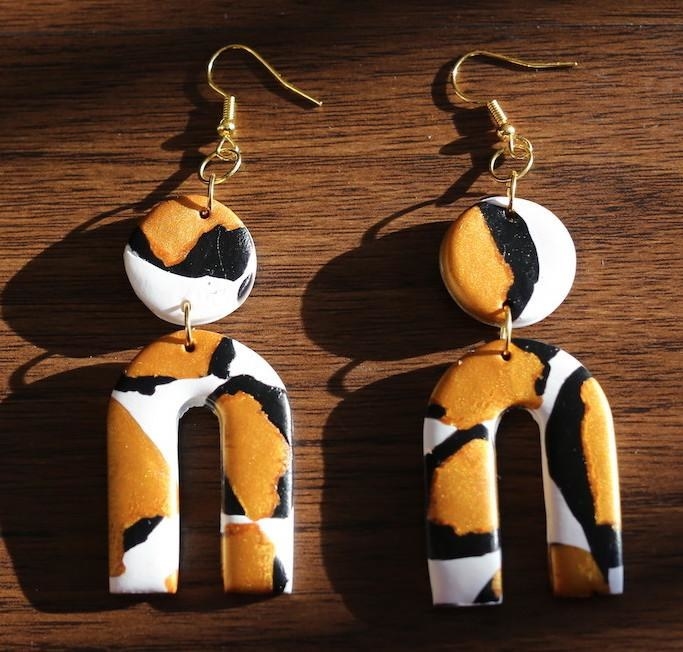 clay earrings with a circle (like button earrings) and a large u-shape hanging from it. They are black, brown, and white.