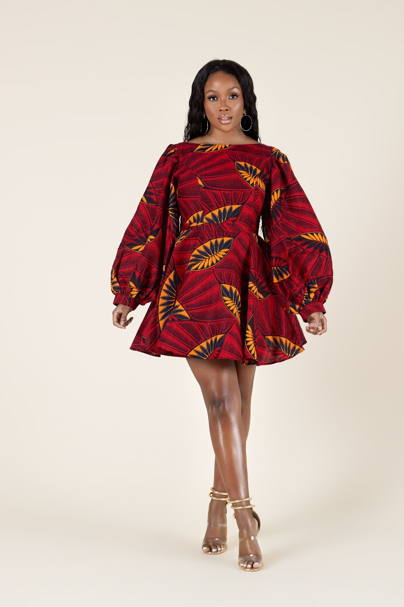 model wearing a short A-line dress with bell sleeves in a red, orange, and black Ankara print