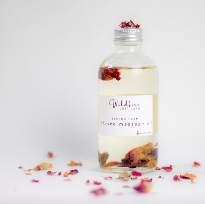 A bottle of massage oil with rosebuds inside the glass bottle