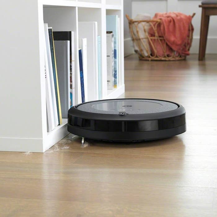 The iRobot cleaning up dust bunnies near a bookshelf