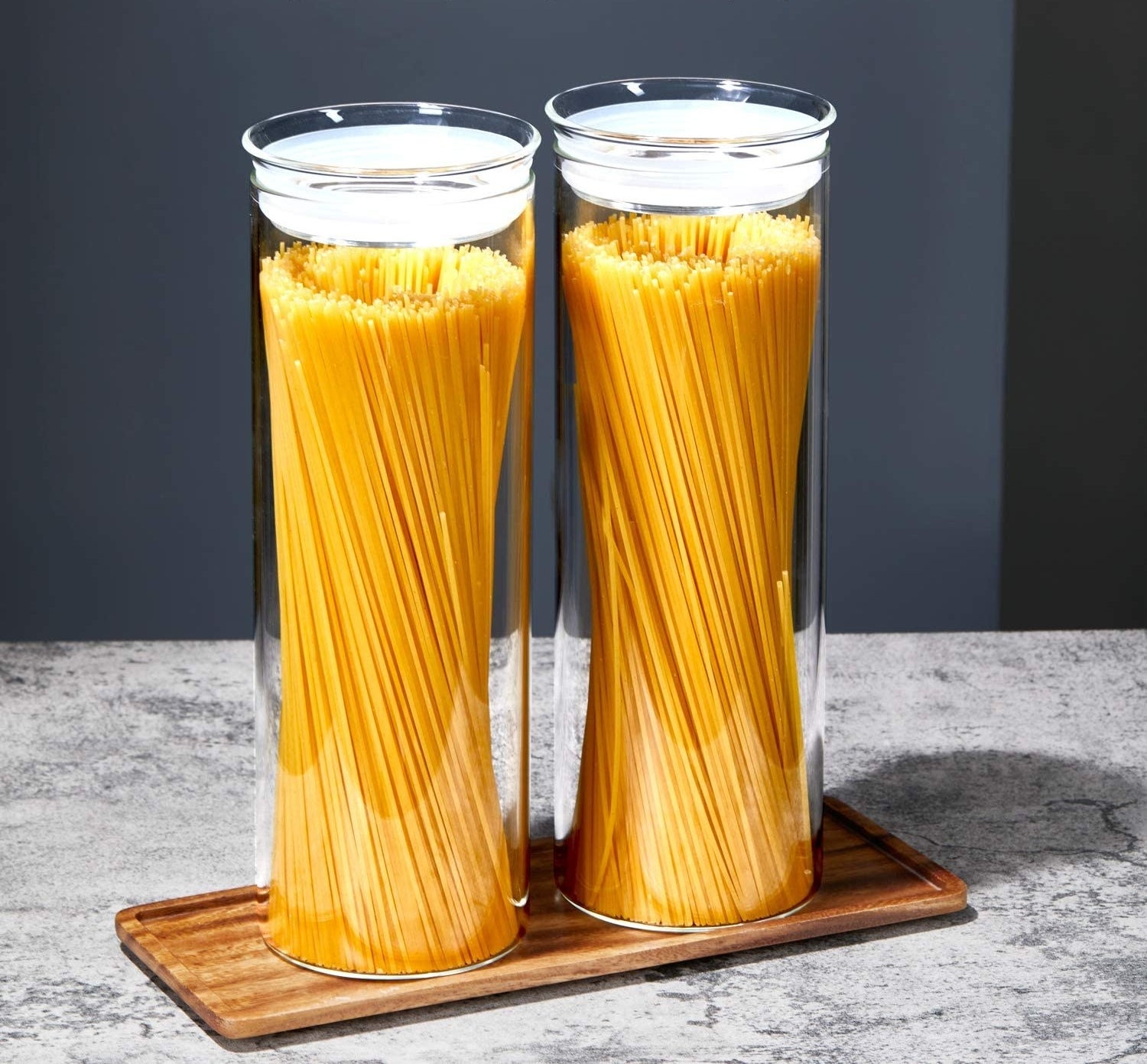 A pair of tall skinny glass canisters filled with spaghetti noodles