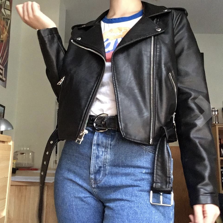 Reviewer showing bottom of jacket with belt at hip and asymmetrical front zipper 