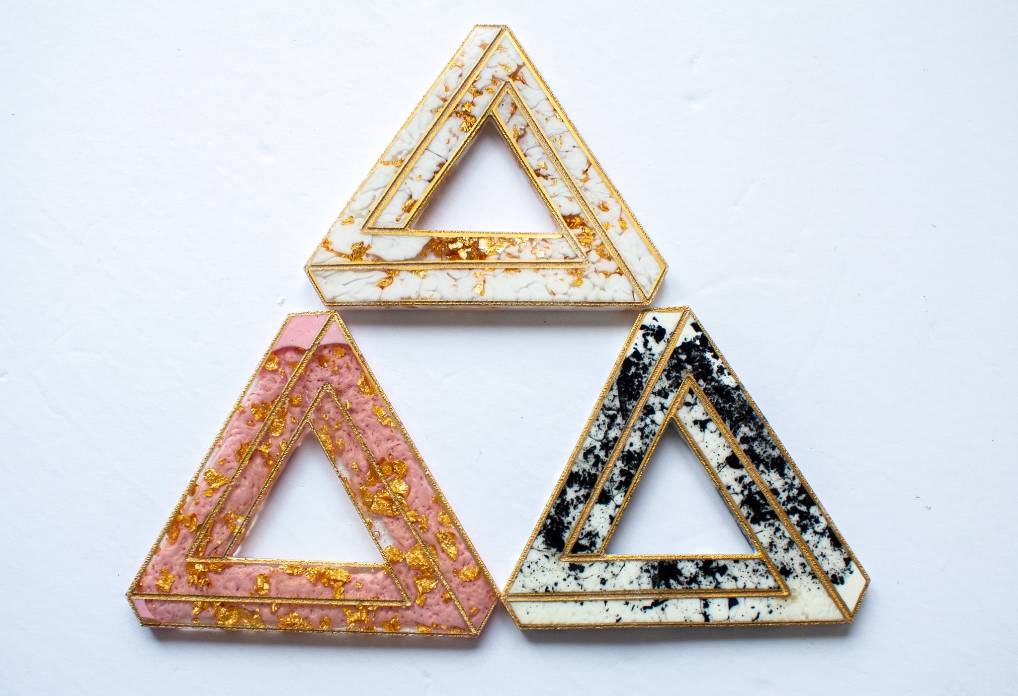 three impossible triangle shapes in pink, white, and black 