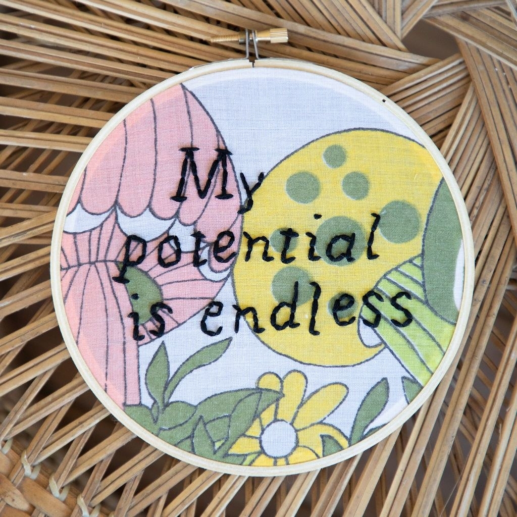 a floral hoop with &quot;my potential is endless&quot; embroidered in black