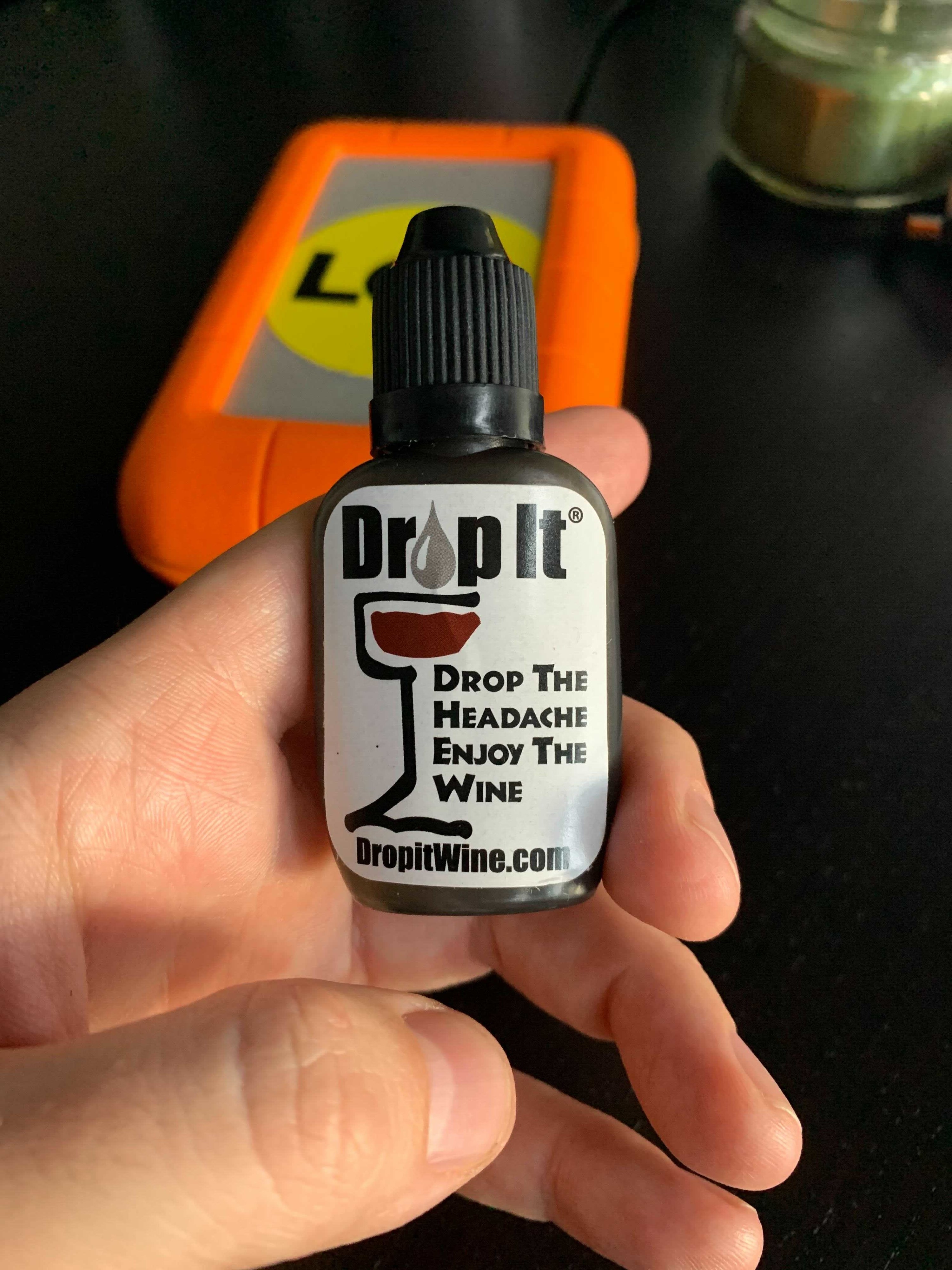 A bottle of Drop it in a hand  against a dark background