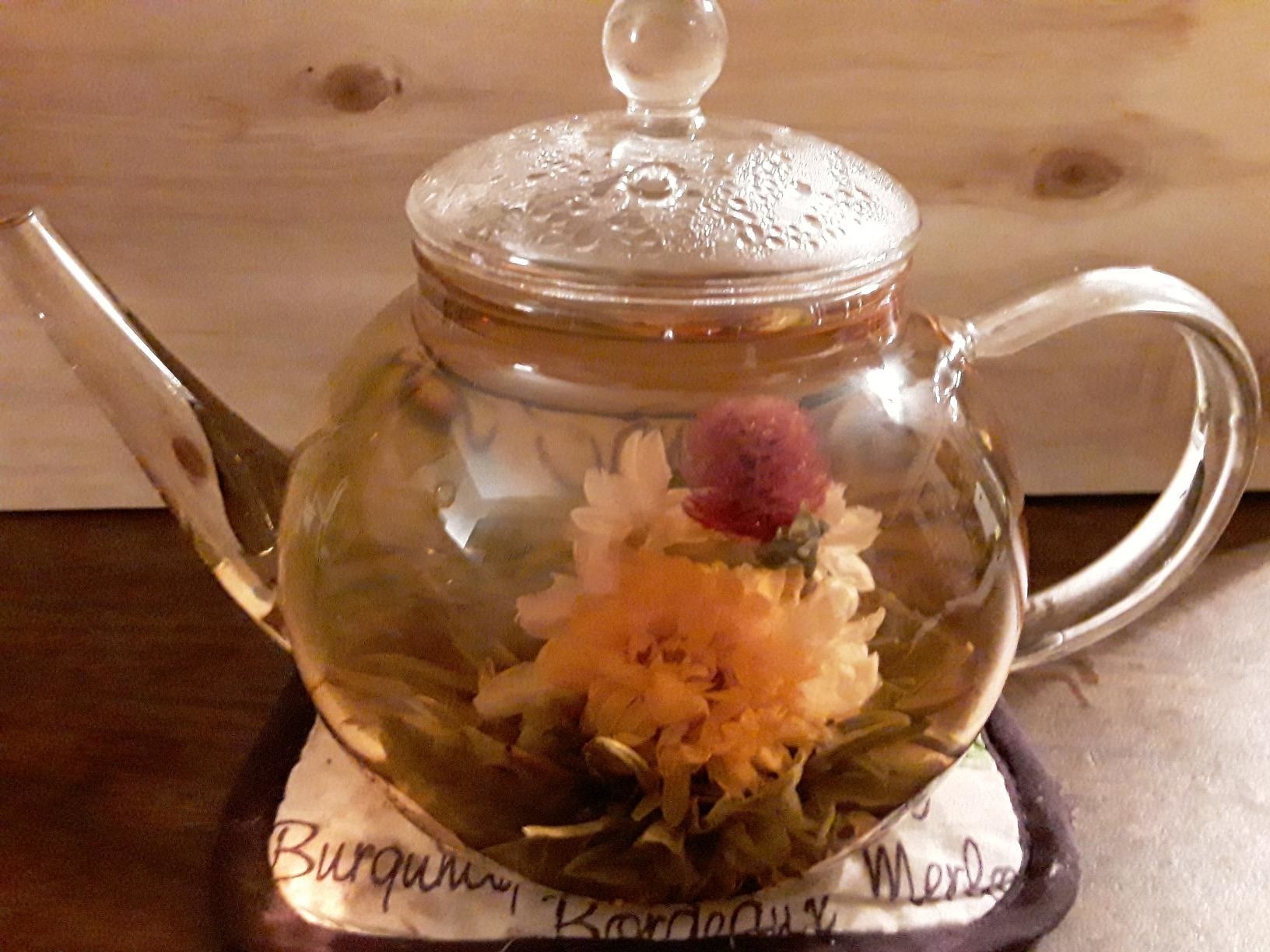 clear teapot with blooming flowers in tea