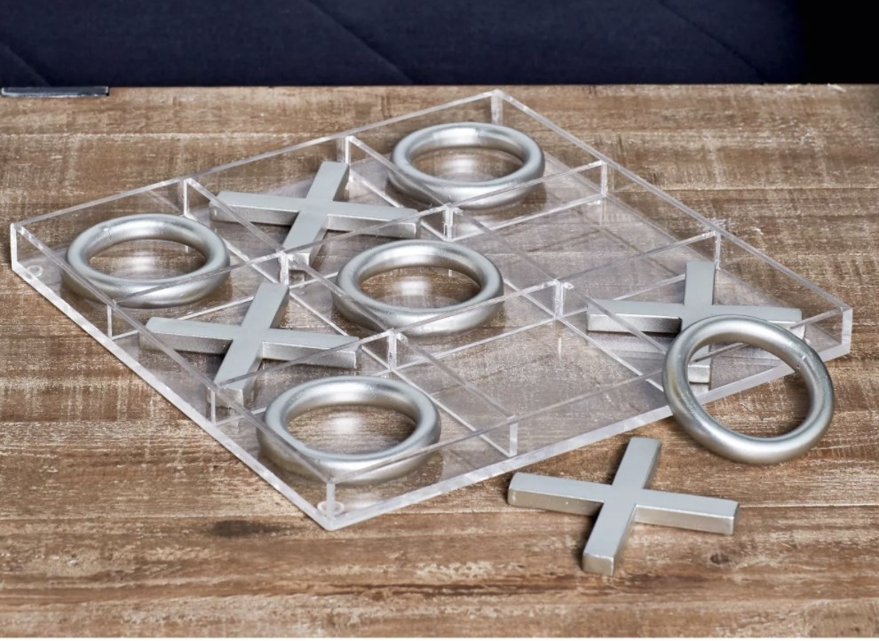 the tic tac toe set with silver pieces on top of a wood table