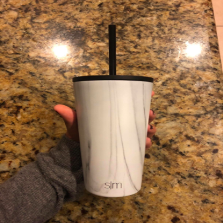 hand holding a marble print tumbler