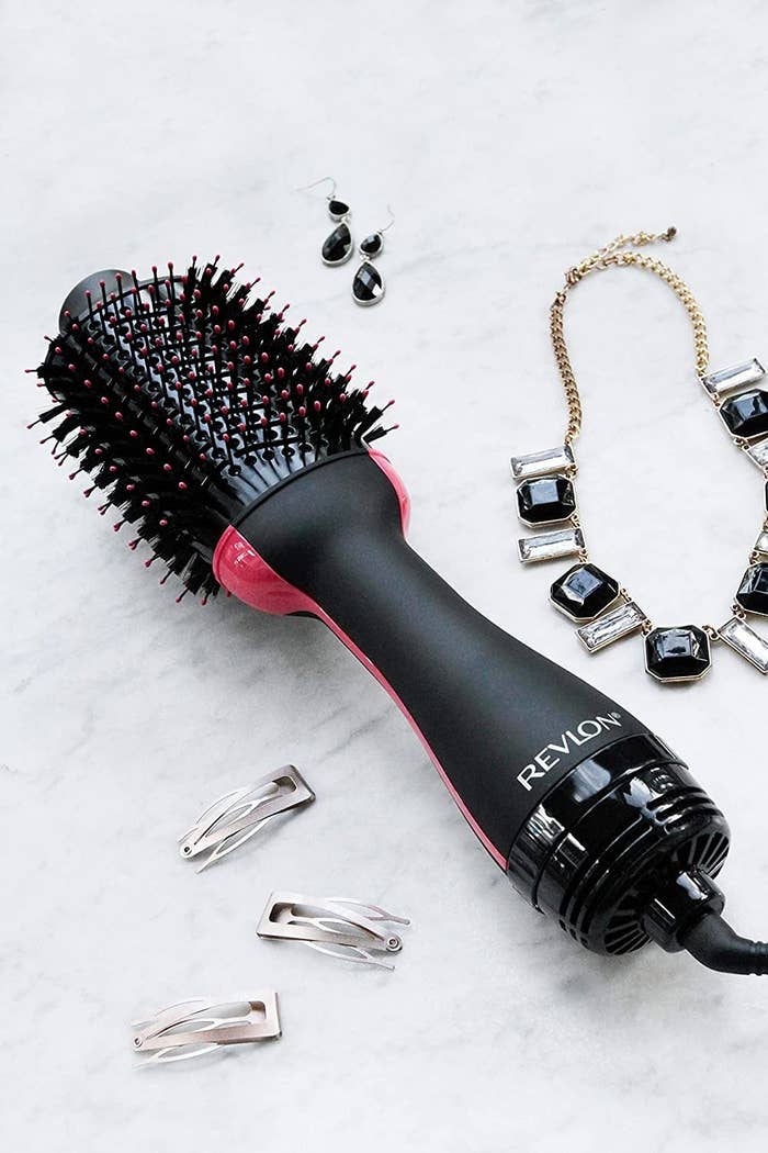 revlon hair dryer brush on a table surrounded by clips, earrings, and a necklace