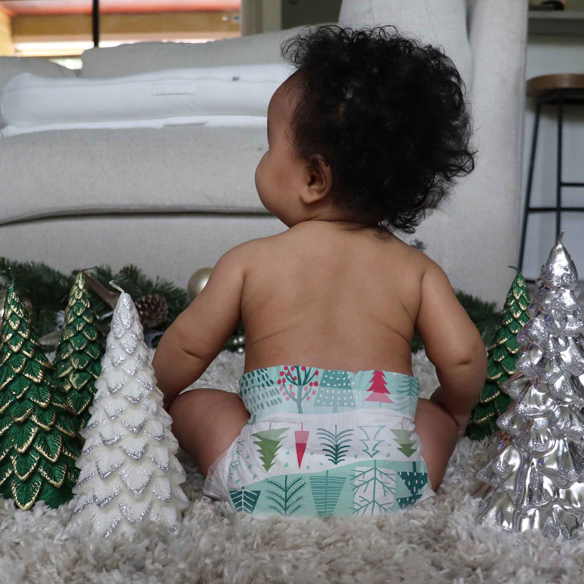 Baby wearing diaper with Christmas tree print on it