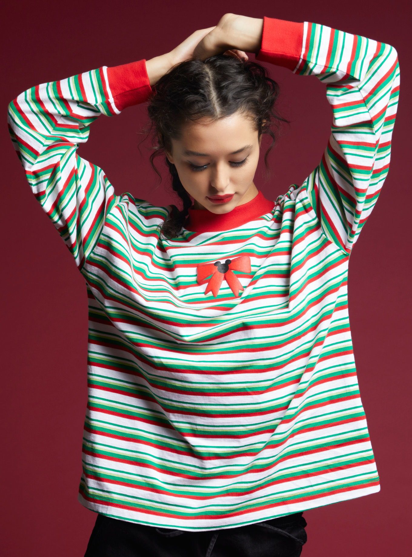 a model in a long sleeve with white, green and red horizontal stripes and a tiny red bow with mickey in the middle 