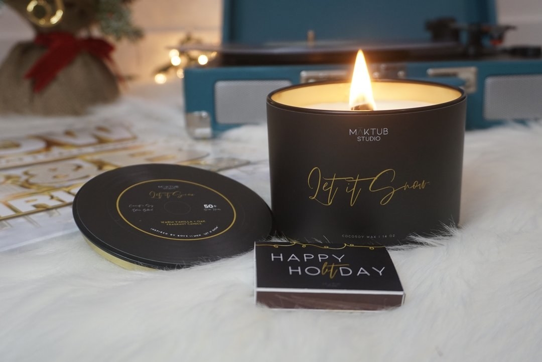 a black lit candle with &quot;let it snow&quot; in script on the front