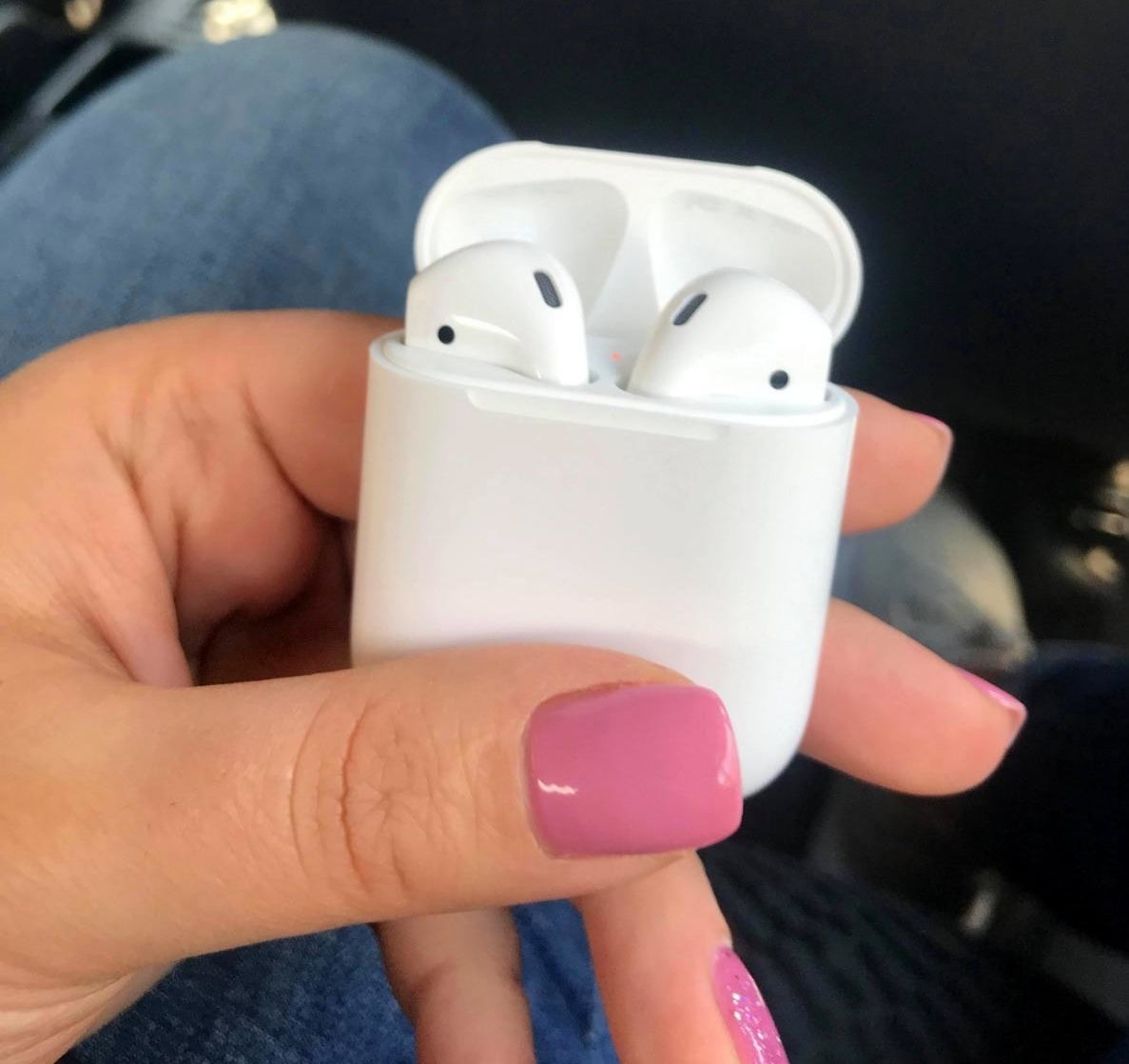 Reviewer holding Apple AirPods with case open