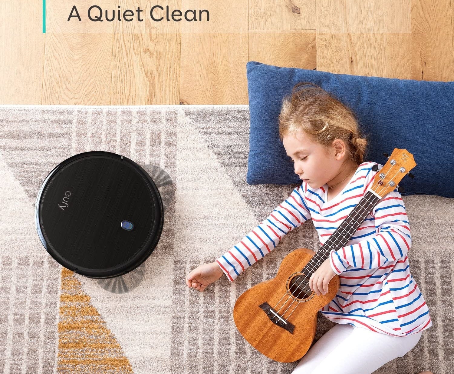 Child holding guitar and sleeping next to Eufy robotic vacuum cleaning the carpet