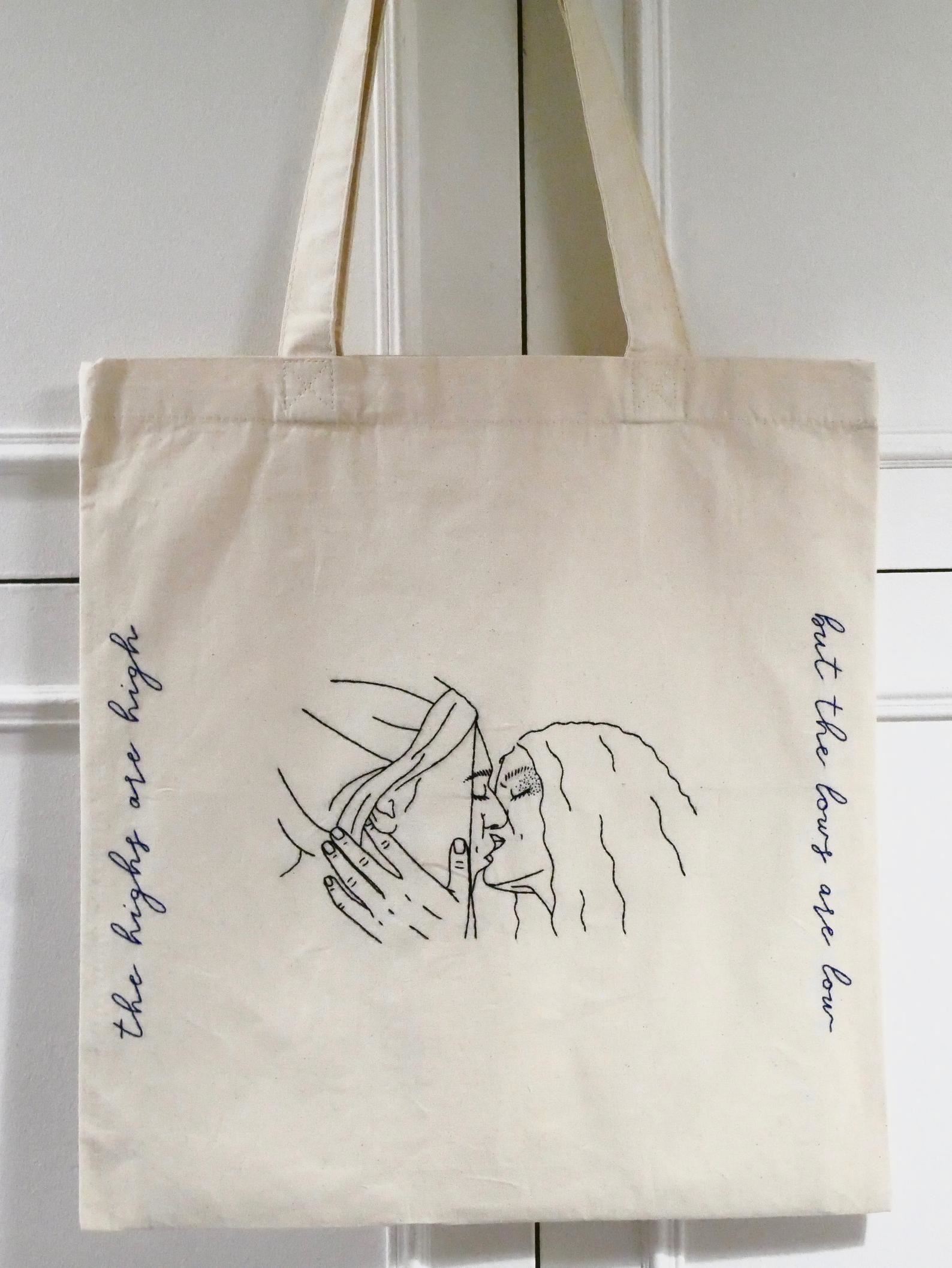 the euphoria hand embroidered tote bag hanging on a door