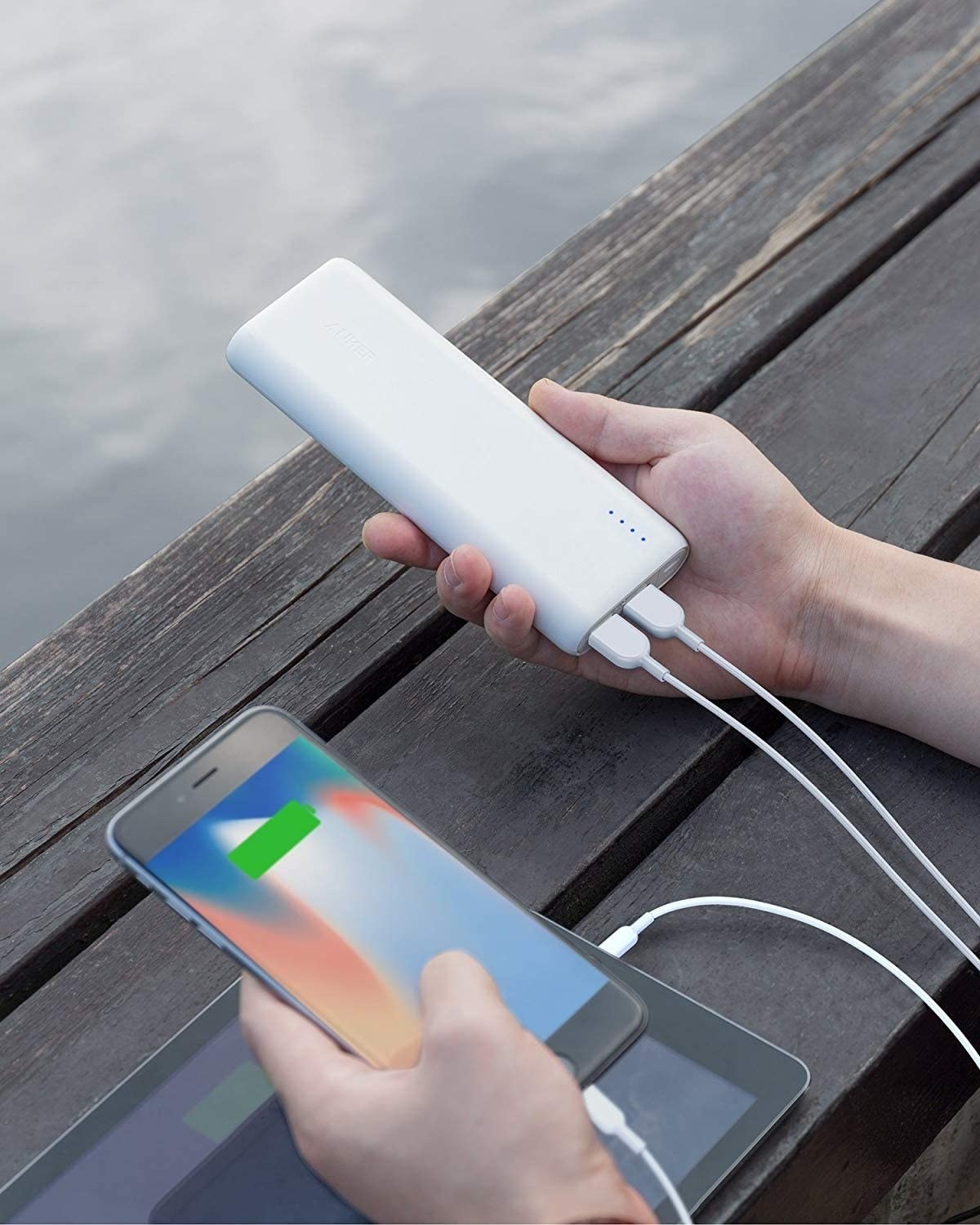 A person holding a slim rectangular power bank charger in their hand