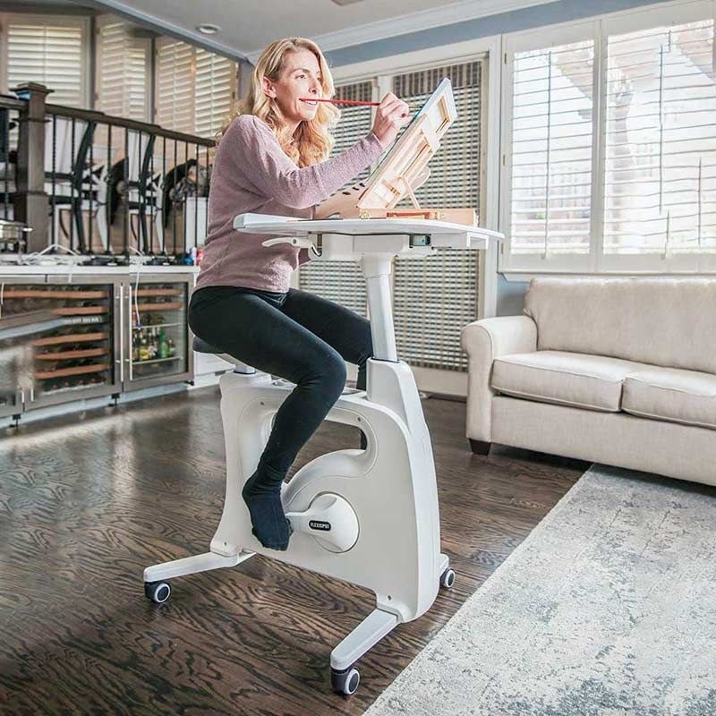 Model sitting at the white stationary bike and painting