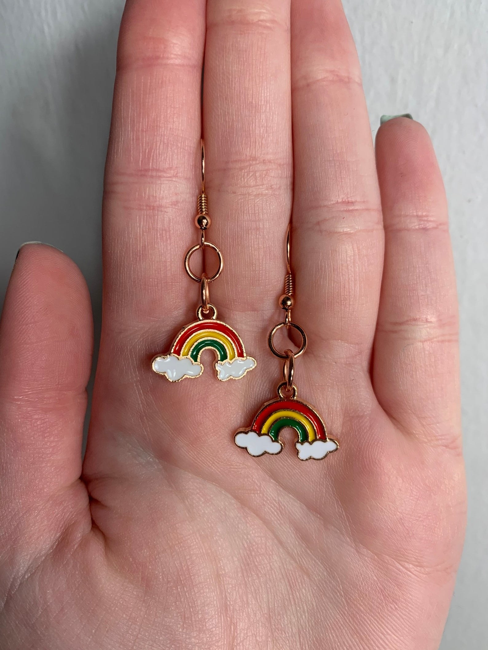 hand holding two earrings shaped like cows