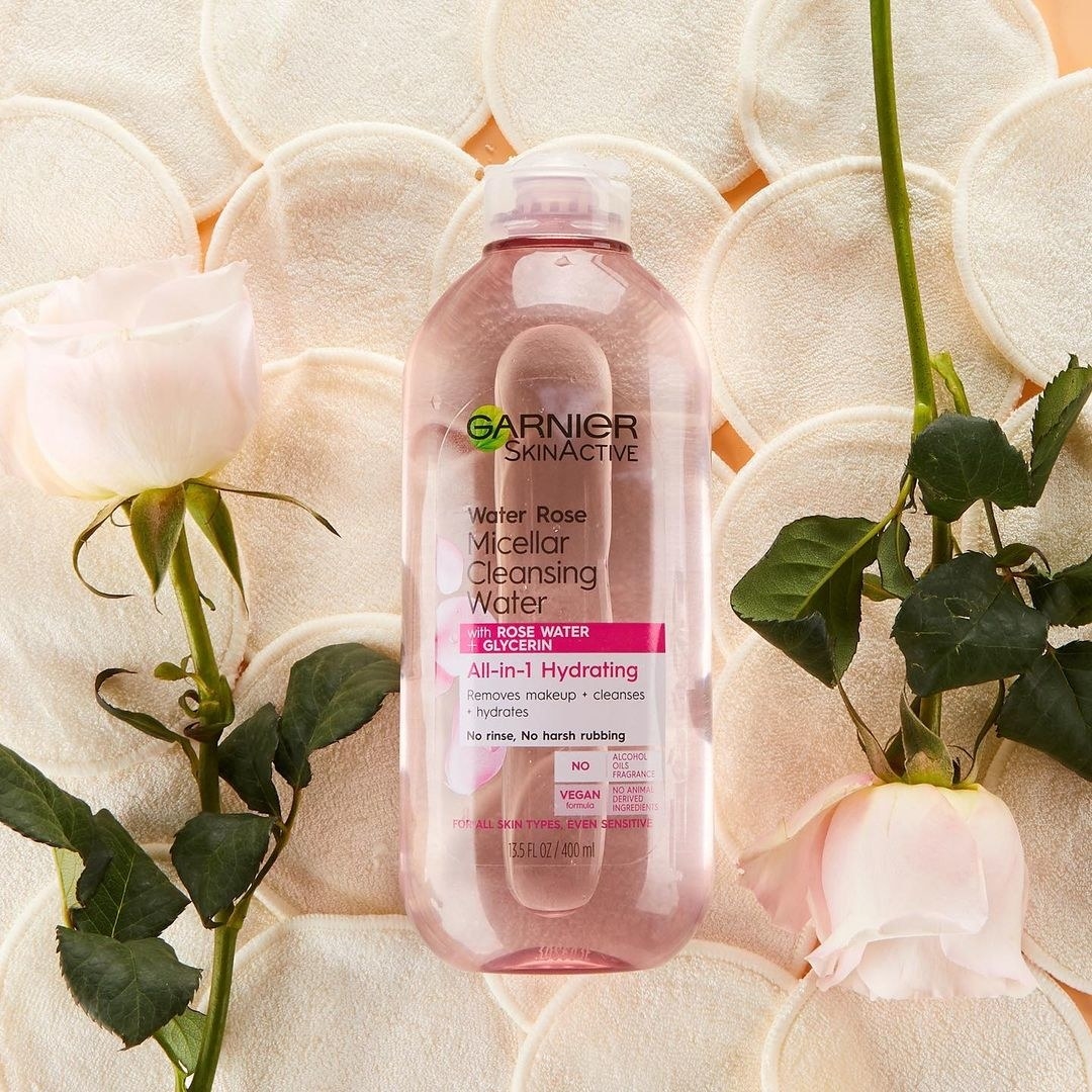 A bottle of rose-infused micellar water on top of reusable cotton pads